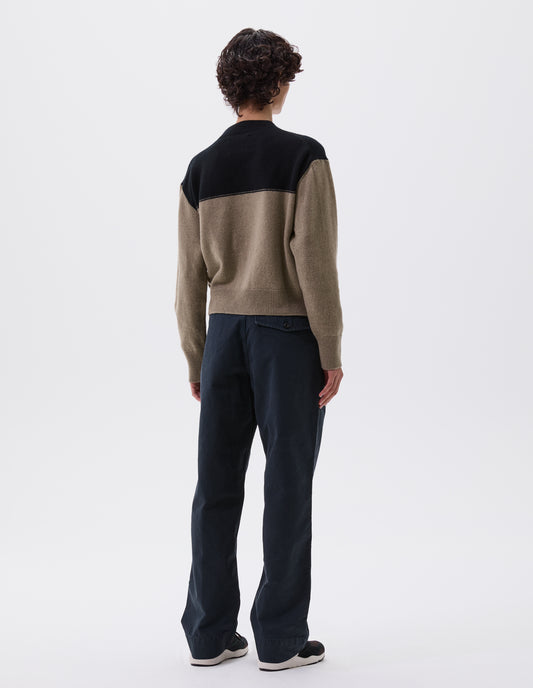 Full body image, back view of model wearing cropped black and beige jumper with ribbed crew neck, cuffs and hem. Styled with black trousers and black, brown and white trainers.