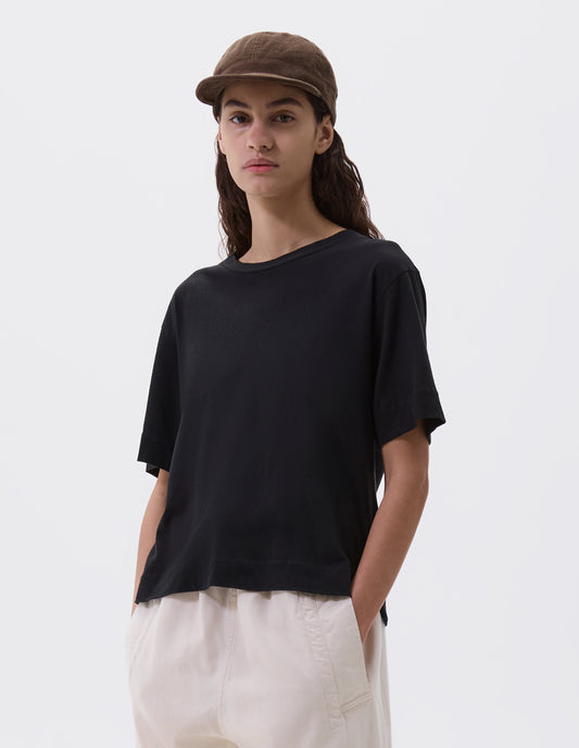 Cropped body image, front view of female model wearing khaki beige corduroy cap. Styled with black t-shirt and off white trousers.