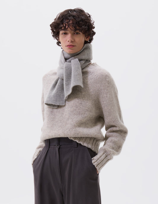 Cropped body image, front view of female model wearing grey knitted wool scarf. Styled with beige jumper and grey belted trousers.