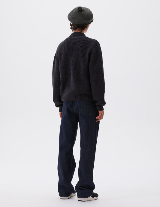 Full body image, back view of model wearing dark grey cardigan with ribbed collar, cuffs and hem. Styled with dark blue jeans, dark green beret and black, brown and white trainers.