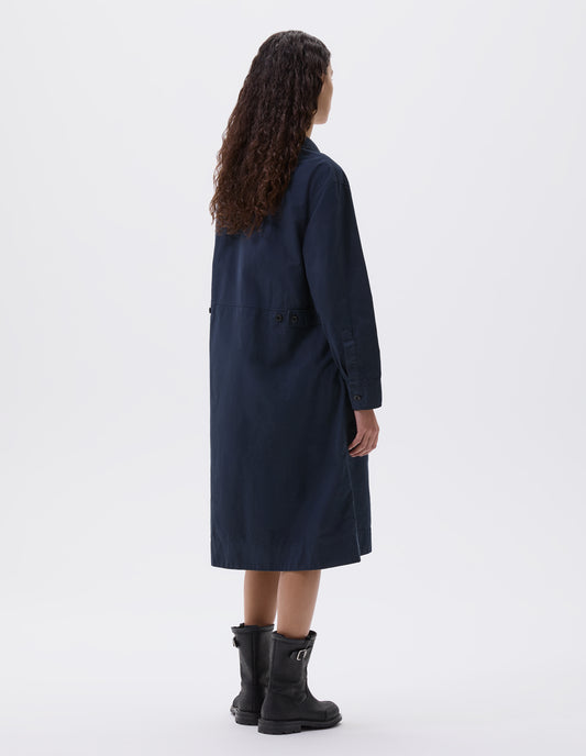 Full body image, back view of model wearing dark blue long sleeve shirt dress with deep stitch hem and waist seam detail with button tab adjusters. Styled with black leather biker boots.