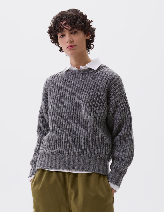 Cropped body image, front view of model wearing grey crew neck jumper with contrasting rib on neck, cuffs and hem. Styled over a white shirt and with green trousers.