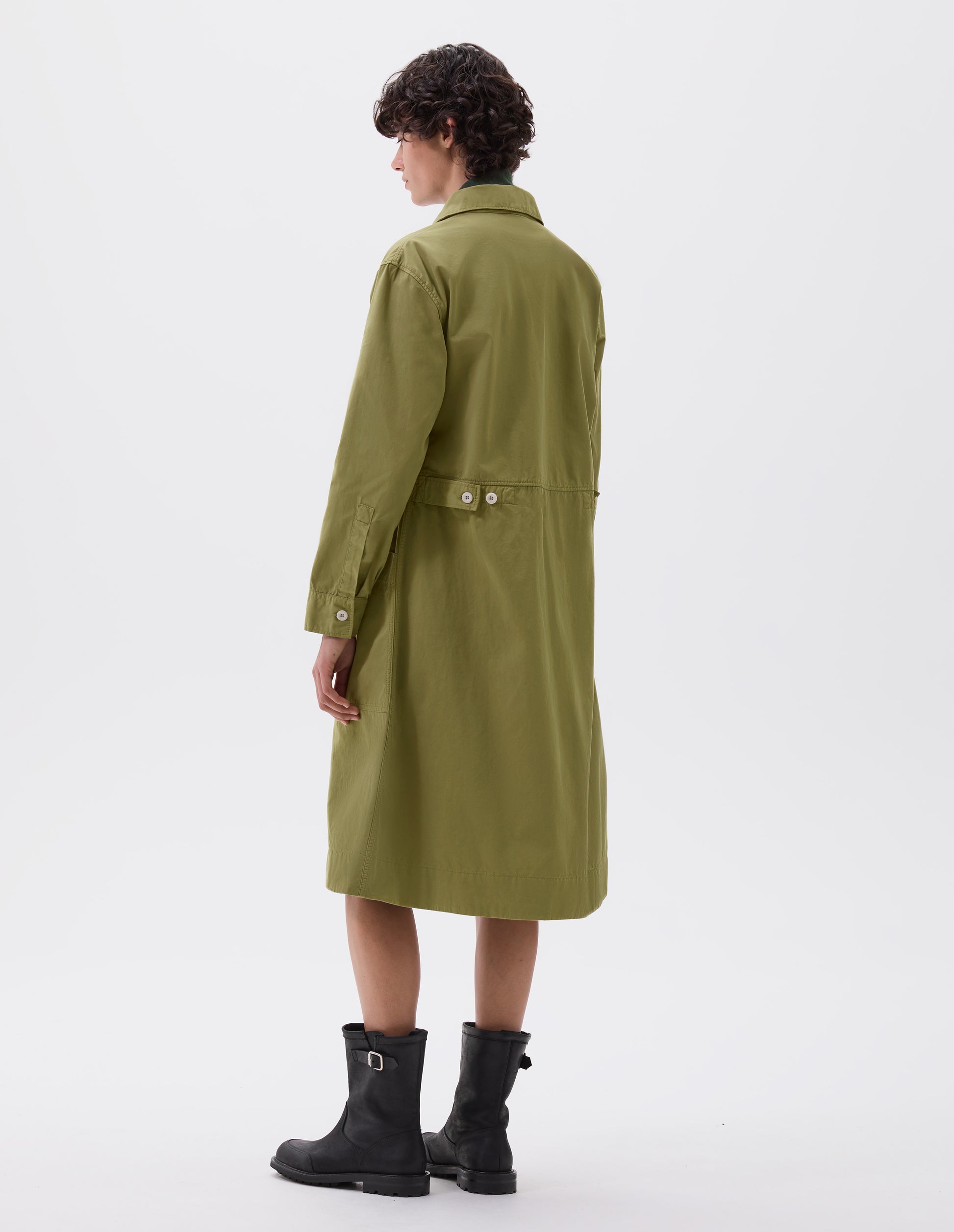 Full body image, back view of model wearing green long sleeve shirt dress with deep stitch hem and waist seam detail with button tab adjusters. Styled with black leather biker boots.