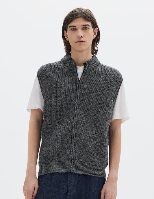 Cropped body image, front view of model wearing grey knitted wool sleeveless gilet, with rib neck, armholes and hem, and a Vislon zip. Styled over white t shirt, with blue denim jeans.