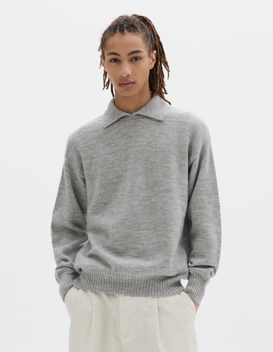Cropped body image, front view of model wearing a light grey wool collared sweater  with a wide rib linked on collar, plain knit body, and deeper ribbed cuffs. Styled with white pleated trousers.