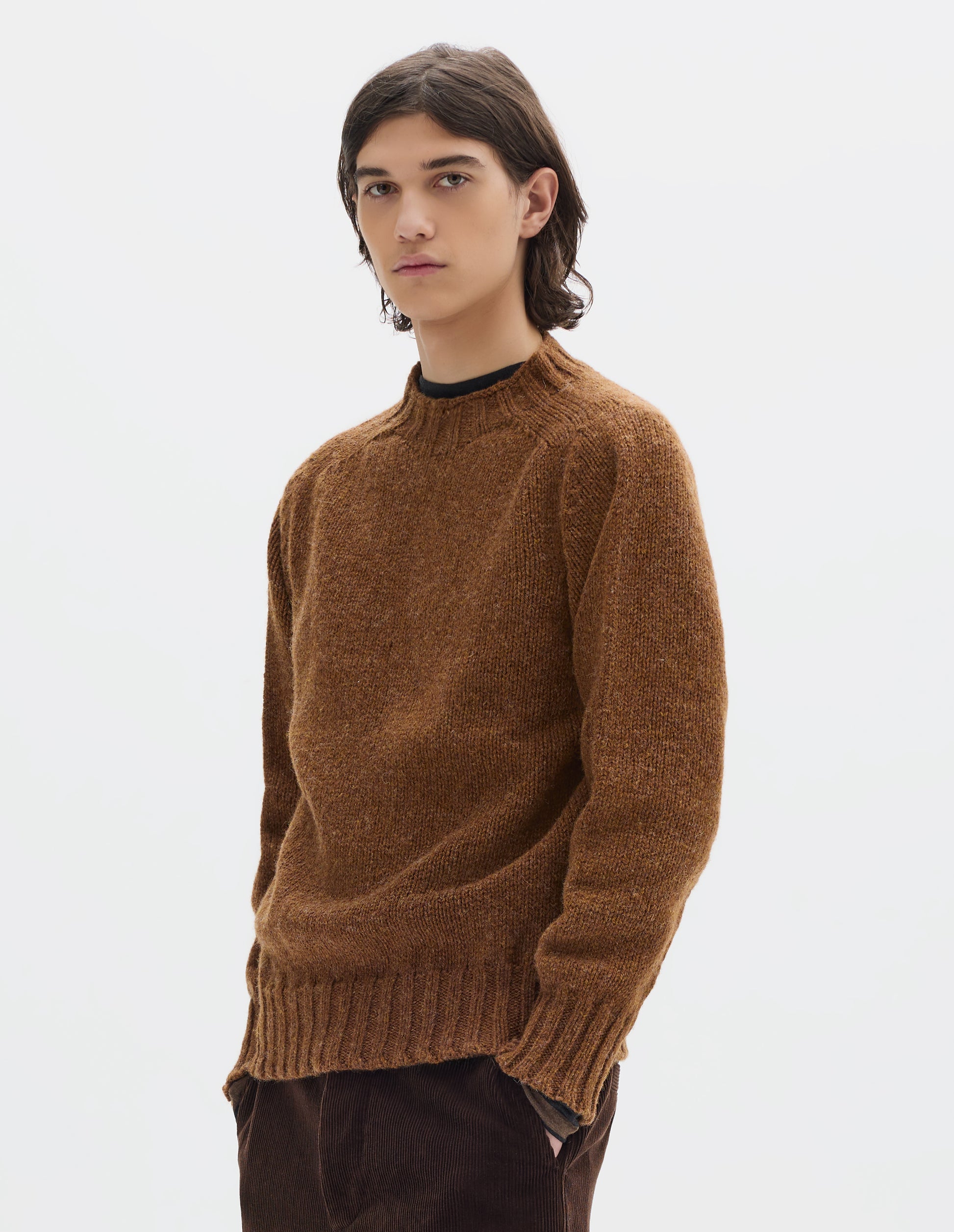 Cropped body image, front view of model wearing orangey brown long sleeve wool jumper, with contrast ribbing on neckline, cuffs and hem. Styled with brown cotton corduroy trousers.