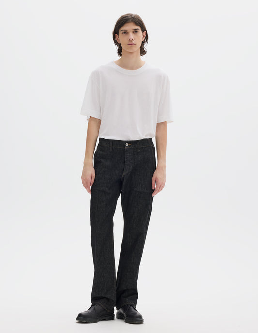 Full body image, front view of model wearing black denim twill jeans, with metal button fly, grown on waistband with belt loops and stitch-through slant pockets. Styled with white short sleeve T shirt and black leather shoes.