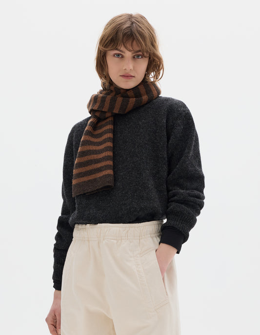 Cropped body image, front view of model wearing a tonal brown stripe wool scarf, a dark grey wool sweater and an off white joggers with elasticated waist and deep welt pockets.