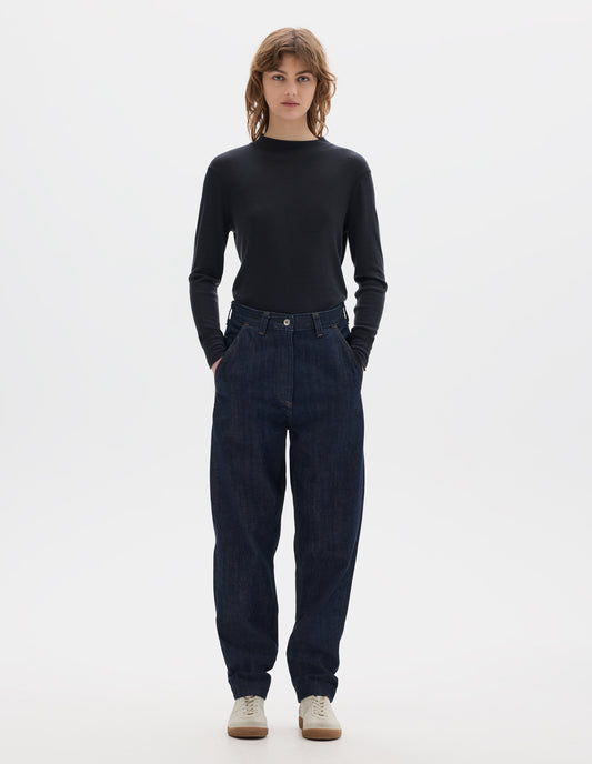 Full body image, front view of model wearing  relaxed dark blue jeans with slant side pockets. Styled with an off black long sleeve thermal t shirt and beige suede trainers.