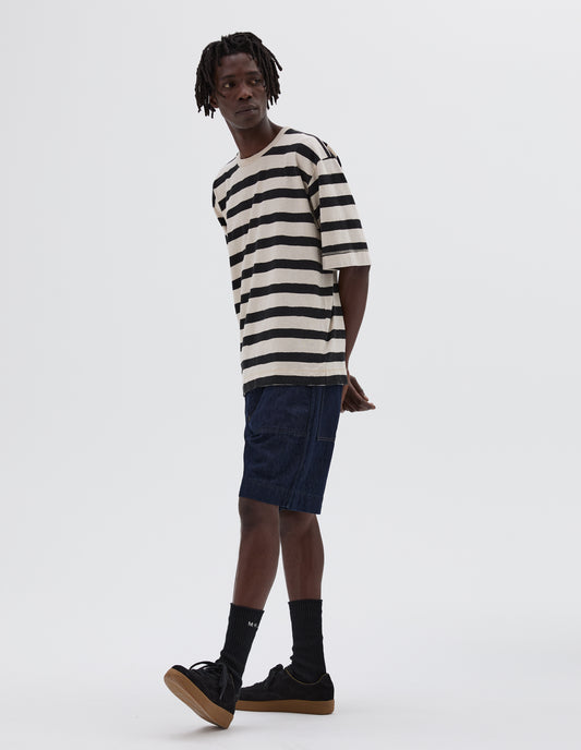 Full body image, front view of model wearing white and black striped t-shirt with contrast rib neck. Styled with denim shorts, black socks and black nubuck trainers.