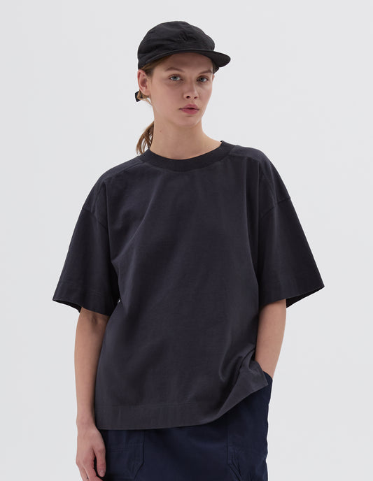 Cropped body image, front view of female model wearing black soft peak cap with contrast herringbone tape slide adjustor detailing. Styled with black t-shirt and navy blue skirt.