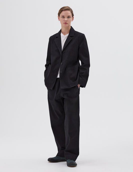 Full body image, front view of model wearing relaxed dark blue joggers with elasticated waist and deep welt pockets. Styled with matching dark blue blazer, white t-shirt and black leather sandals.
