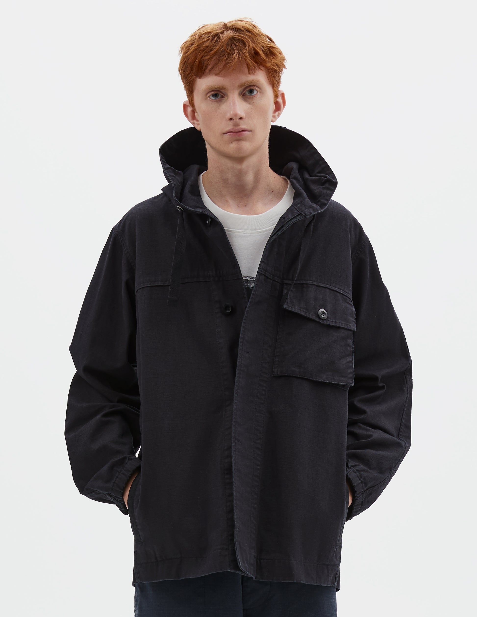 Cropped body image, front view of model wearing indigo blue twill hooded jacket, with flap patch chest pocket, concealed placket, drawcord adjustable hood and elasticated cuffs. Styled over white graphic t-shirt, with navy blue shorts.