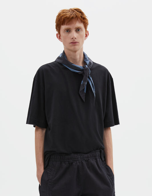 Cropped body image, front view of model wearing a Greyish blue and dark blue striped cotton scout scarf. Styled with a dark blue t-shirt and dark blue trousers.