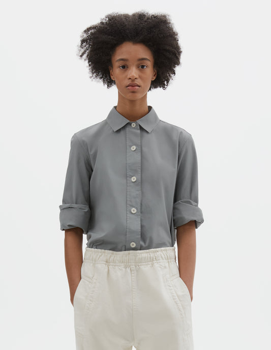 Cropped body image, front view of model wearing grey regular cut shirt with stitch through raised placket with corozo buttons on placket and cuffs. Styled with beige joggers.