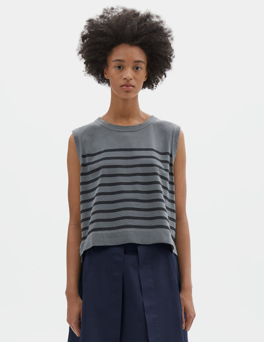 Cropped body image, front view of model wearing blue cotton linen tank top with black stripes, contrast ribbing on neckline and armholes, with side splits and deep stitch hem. Styled with a blue skirt.