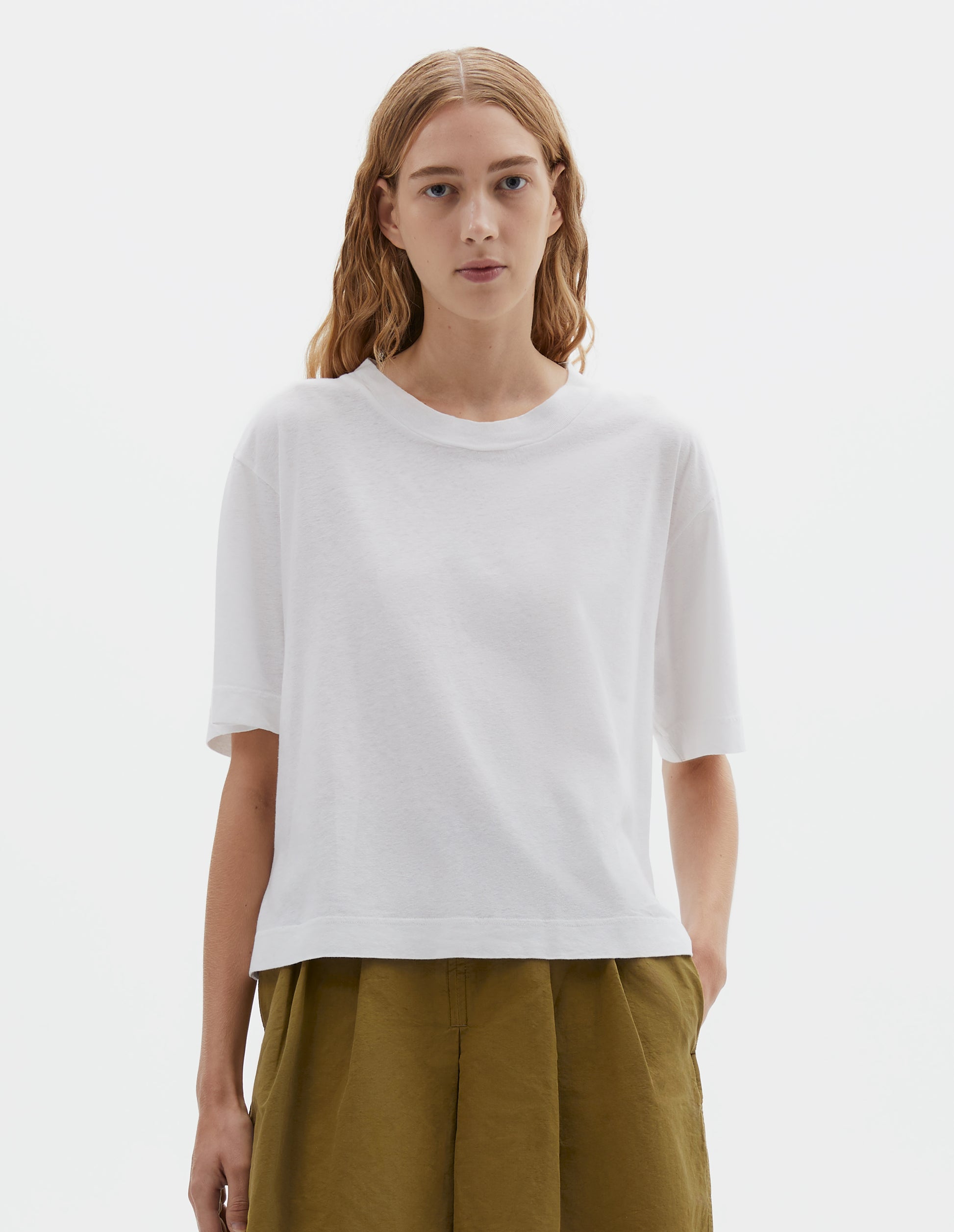 Cropped body image, front view of model wearing white short sleeve cotton t-shirt with contrast rib on neck. Styled olive green shorts.