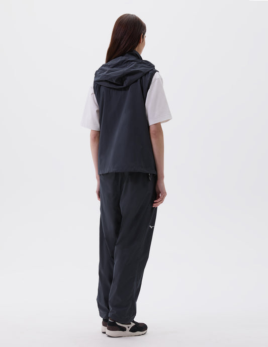 Full body image, back view of model wearing dark blue regular cut gilet with hood, styled with white t-shirt and dark blue trousers with black, brown and white trainers.