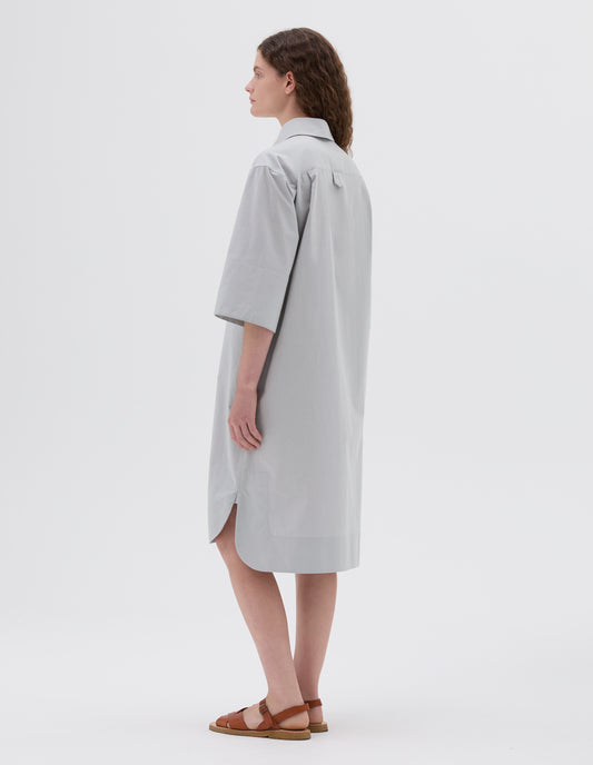 Full body image, back view of model wearing light grey below the knee shirt dress with short sleeves and hanger loop detail on back, styled with light brown leather sandals.