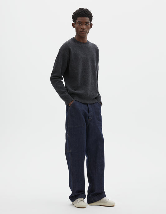 Full body image, front view of model wearing relaxed  dark grey knitted sweatshirt with rib collar, cuffs and hem. Styled with dark blue jeans and beige trainers.