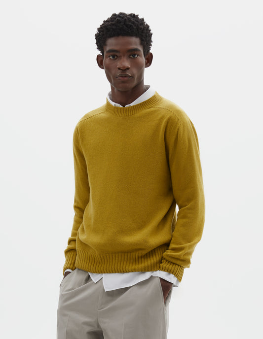Cropped body image, front view of model wearing yellow crew neck jumper with seamless finish and contrast ribs on neck, cuffs and hem. Styled over white cotton shirt, with grey trousers.