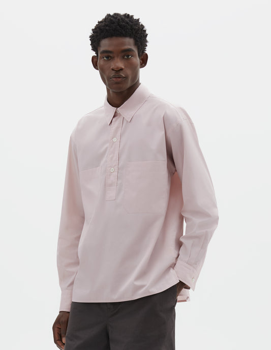 Cropped body image, front view of model wearing pink cotton long sleeve shirt with stitch through raised placket, front patch pockets and deep side split vents. Styled with brown shorts.