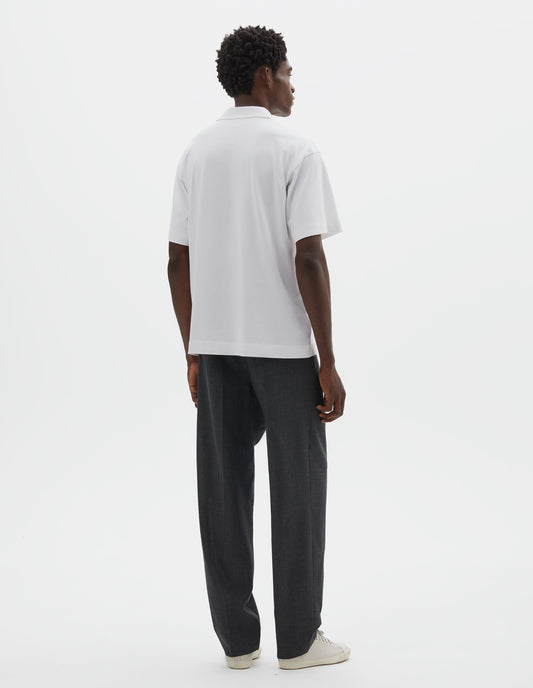 Full body image, back view of model wearing grey crisp wool trousers. Styled with white short sleeve polo shirt and beige canvas trainers.