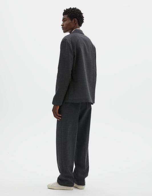 Full body image, back view of model wearing grey crisp wool blazer. Styled with matching grey trousers and beige canvas trainers. 