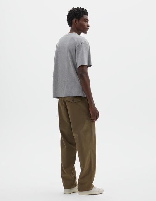 Full body image, back view of model wearing grey cotton short sleeve t-shirt. Styled with green trousers and beige canvas trainers.