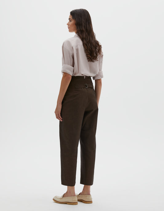 Full body image, back view of model wearing brown cotton linen trousers, with deep waistband and cinch adjustor on centre back seam. Styled with pink shirt, brown tie and beige suede loafers.