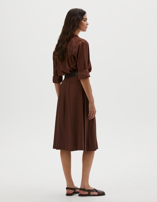 Full body image, back view of model wearing brown matt silk skirt. Styled with matching brown shirt, black leather belt and brown leather sandals.