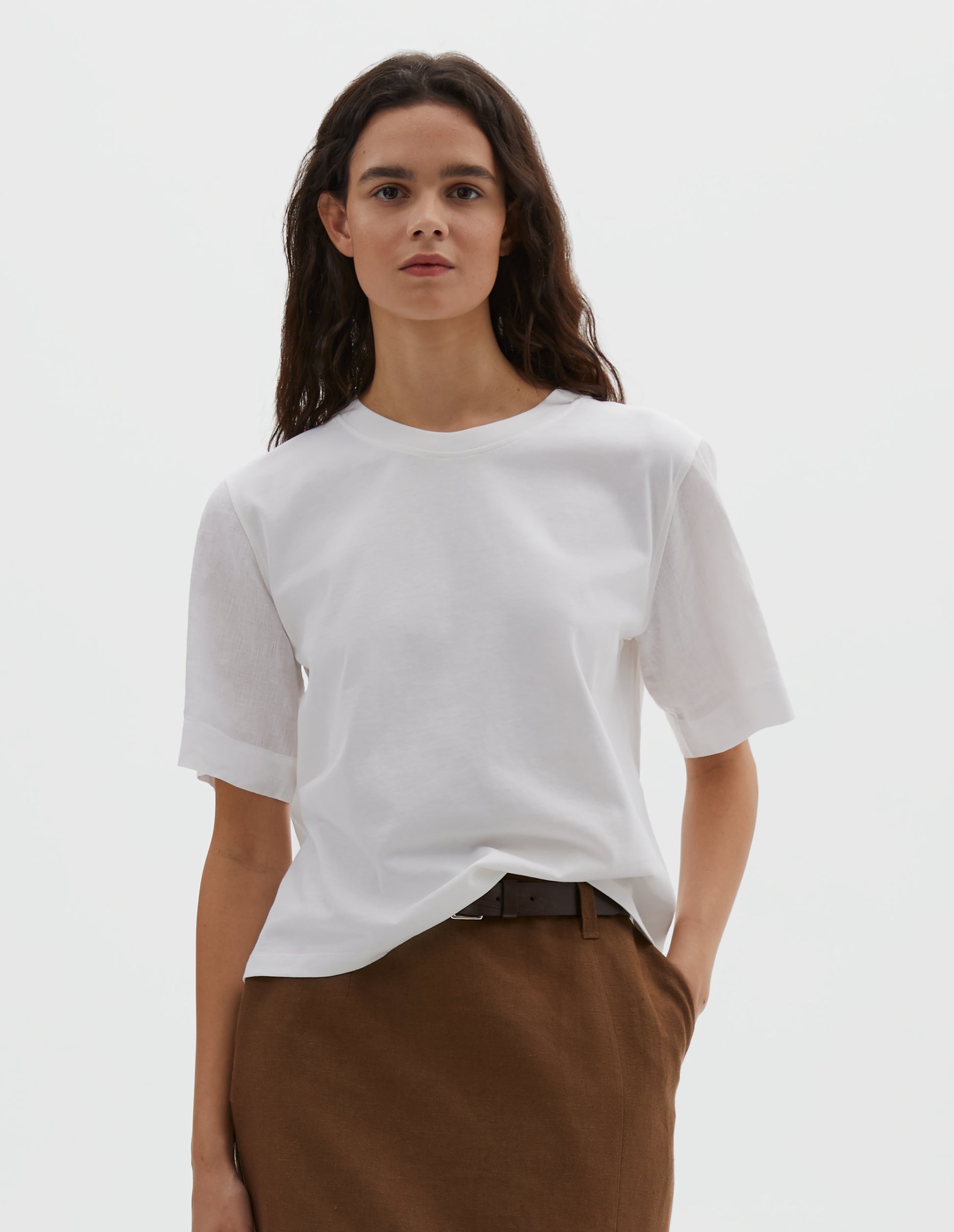 Cropped body image, front view of model wearing white regular cut t-shirt with contrast Irish shirting linen sleeve. Styled with a brown skirt.