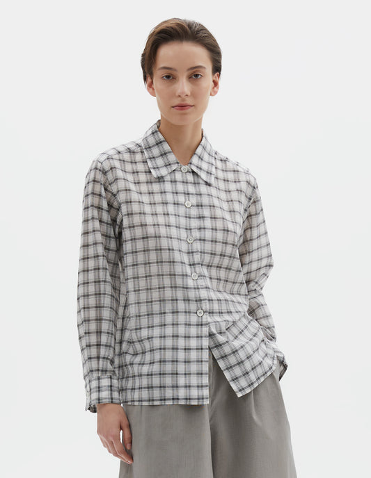 Cropped body image, front view of model wearing white with black check shirt with a curved collar, side split hem. Styled with black and beige fine stripe shorts.