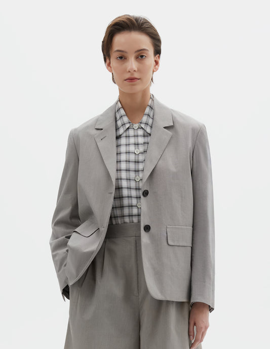 Cropped body image, front view of model wearing black and cream stripe cotton silk blazer with horn button fastening lapel, horn button cuffs and two flap concealed pockets. Styled over black and white checked shirt, with matching black and cream stipe cotton silk shorts.