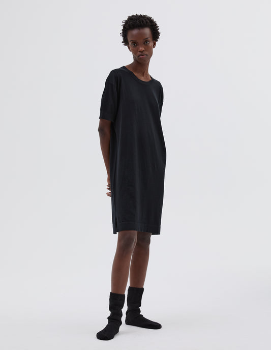 Full body image, front view of model wearing black cotton night t shirt, with short sleeve and round neck. Styled with black bed socks.