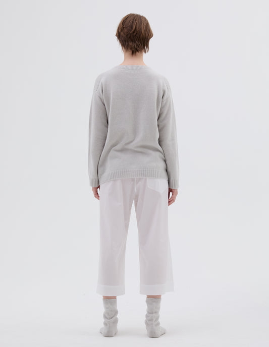Full body image, back view of model wearing light grey merino cashmere bed jumper with raglan sleeve and contrast rib on neck, cuffs and hem. Styled with white cotton cropped PJ pants and light grey bed socks.