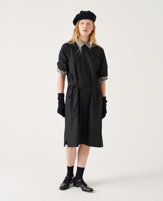 Full body image, front view of female model wearing black cashmere merino knitted gloves with contrasting rib cuffs. Styled with black short sleeve t-shirt dress over grey striped shirt with rolled up sleeves, and with black beret, black knitted gloves, black socks and black leather shoes.
