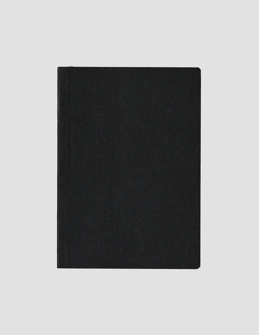 A flat lay view of the black paper cloth notebook cover with the grey ribbon bookmark just visible.