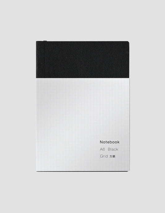 A flat lay view of the black notebook with white wrap around label and the grey ribbon bookmark just visible.