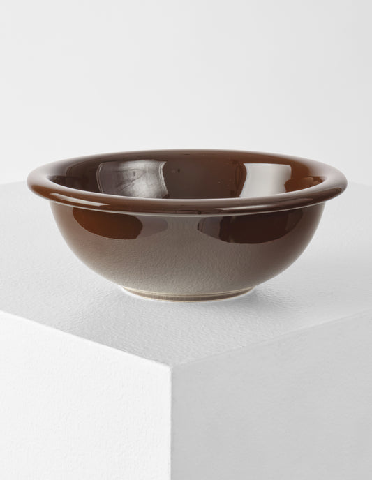 A single brown high gloss stoneware Bronto bowl on a white plinth.