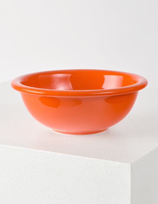 A single orange high gloss stoneware Bronto bowl on a white plinth.