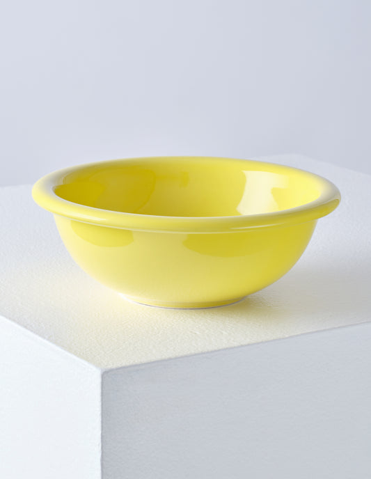 A single yellow high gloss stoneware Bronto bowl on a white plinth.