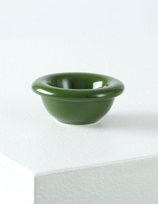 A single green high gloss stoneware Bronto egg cup on a white plinth.