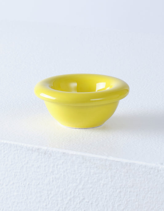 A single yellow high gloss stoneware Bronto egg cup on a white plinth.