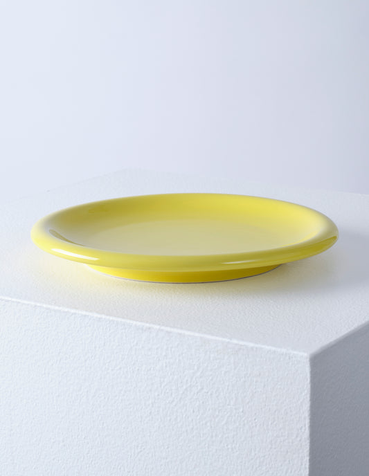 A single yellow high gloss stoneware Bronto plate on a white plinth.