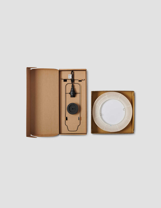 A flat lay view of the two boxes one containing the Hotaru mini buoy cast iron base, metal armature and light fitting. The other showing the concertinaed paper and bamboo shade. 