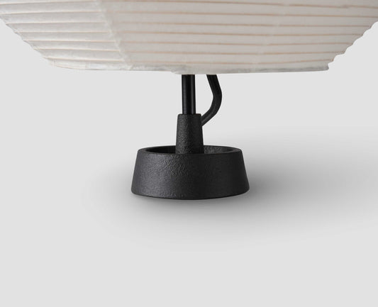 A close up view of the cast iron black base of the Hotaru mini double bubble table light with black metal armature.