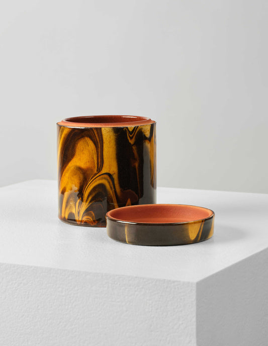 Front flat lay of a round ceramic orange and brown marbled storage jar with lid off. The lid is placed next to pot, showing the terracotta coloured interior.