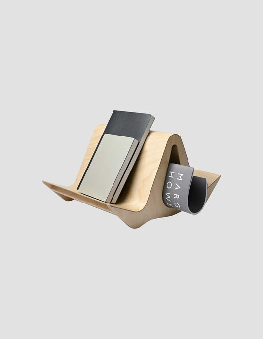 The Isokon Gull bookstand with notebooks on an outer wing and a Margaret Howell lookbook in the newspaper/magazine slot.