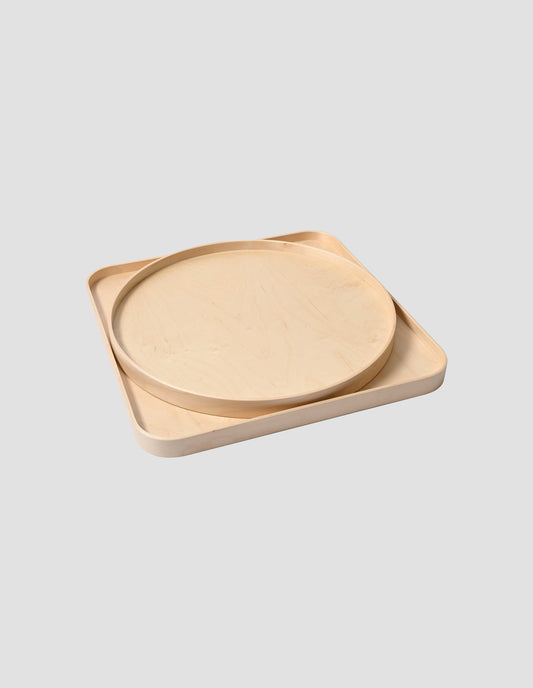 An angled view of the Isokon round tray sitting inside the Isokon square tray.